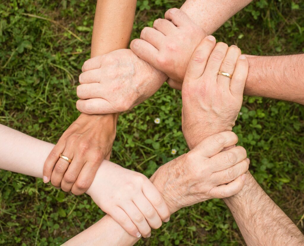 Hands grasping wrists of the next person, all in a circle. 